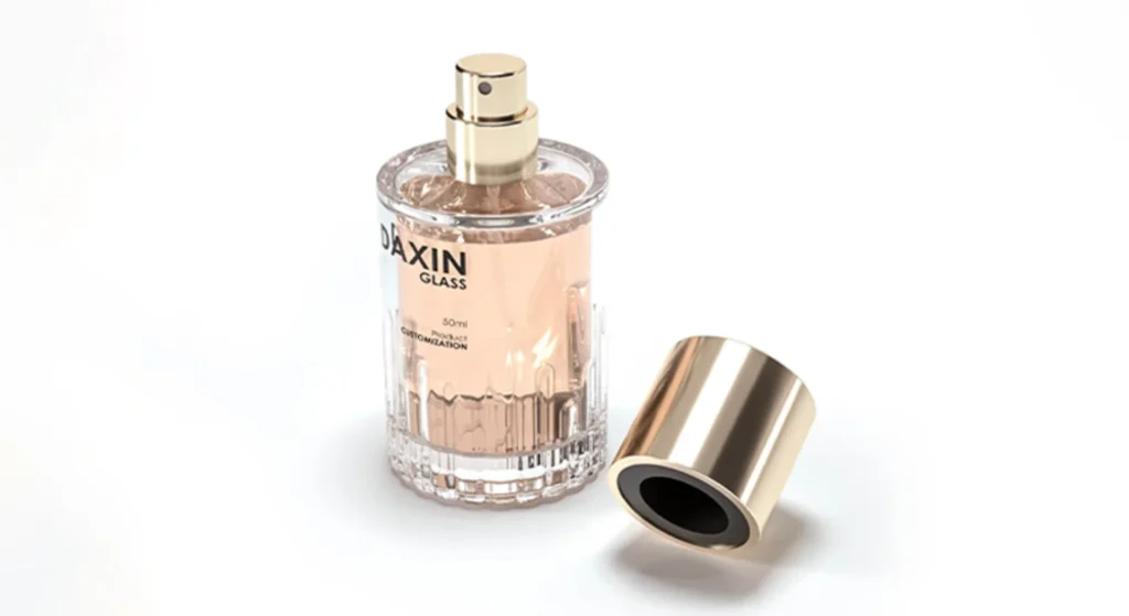 A clear cylindrical glass perfume bottle with a gold spray nozzle and matching gold cap placed beside it, filled with light pink liquid, featuring the brand name DAXIN GLASS on the front.