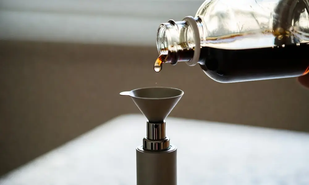 Perfume being poured into a small refillable travel atomizer using a funnel